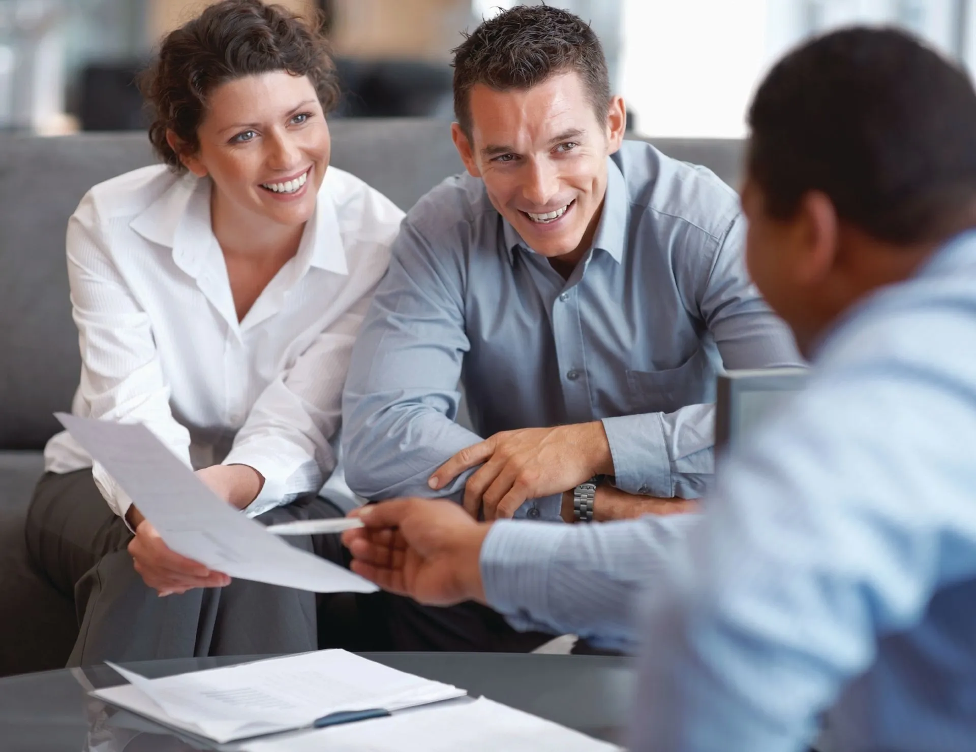 A couple reviewing paperwork with an agent in an office.